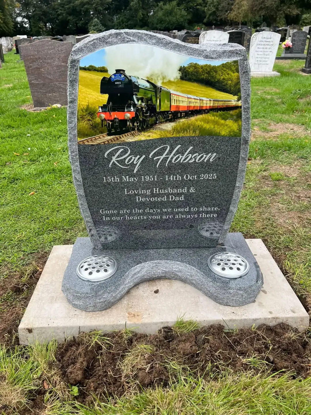 Installed mid-grey granite lawn headstone with a personalised train design