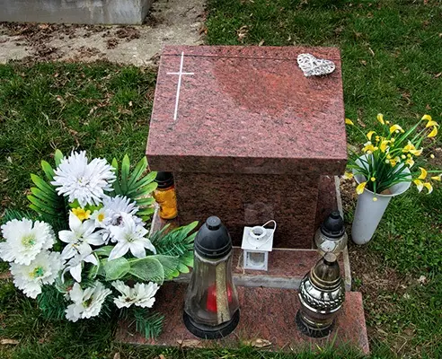 Red granite cremation memorial with flower containers and lanterns